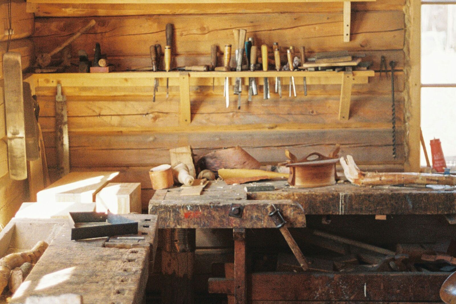 Werkbank in einer Holzwerkstatt, darüber ein Bord mit Stecheisen, Feilen und Zangen.